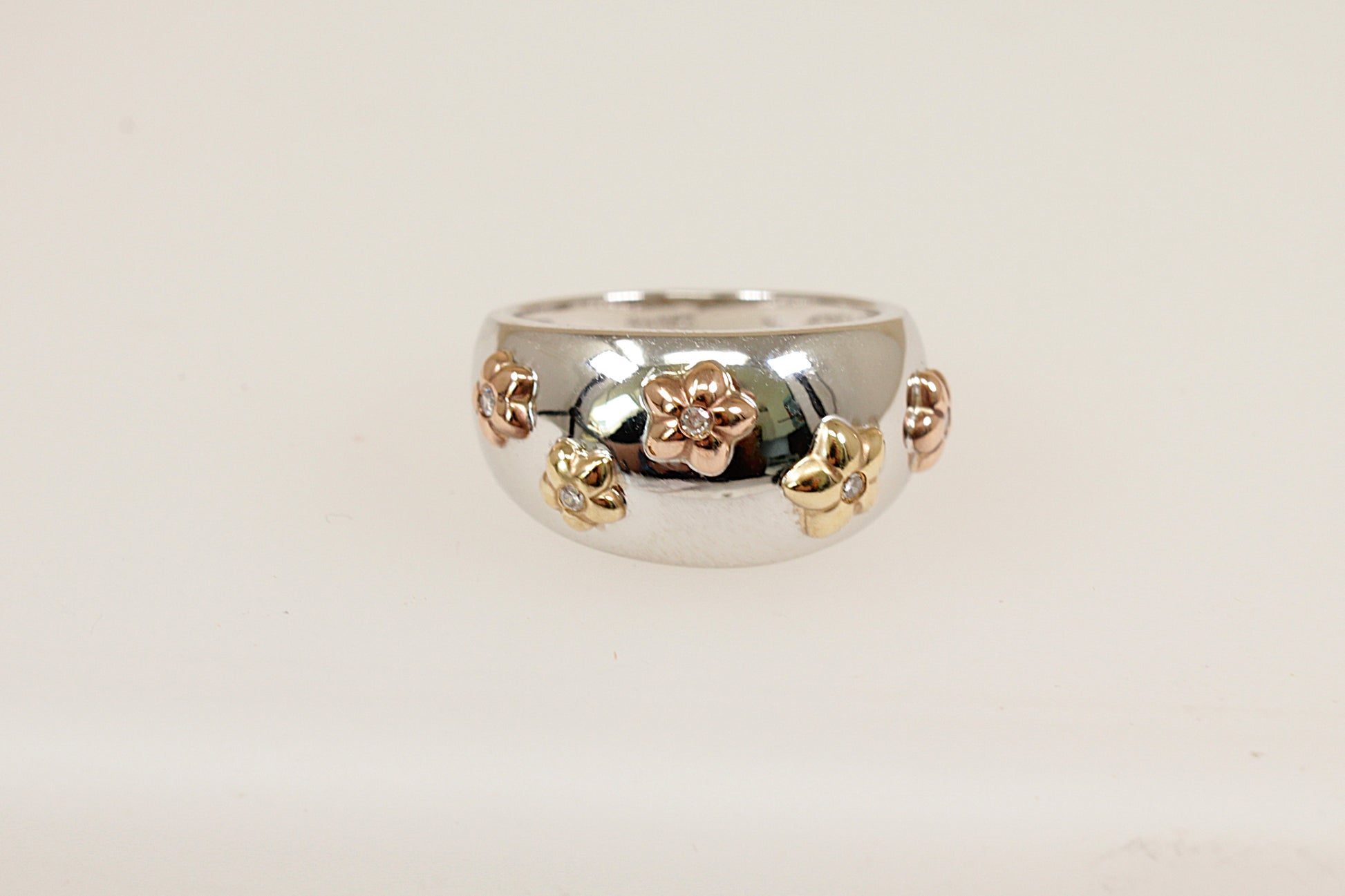 A 9ct white and yellow gold scatter ring on the white gold band it has five yellow gold flower heads each mounted with a central round cut diamond UK finger size O. 