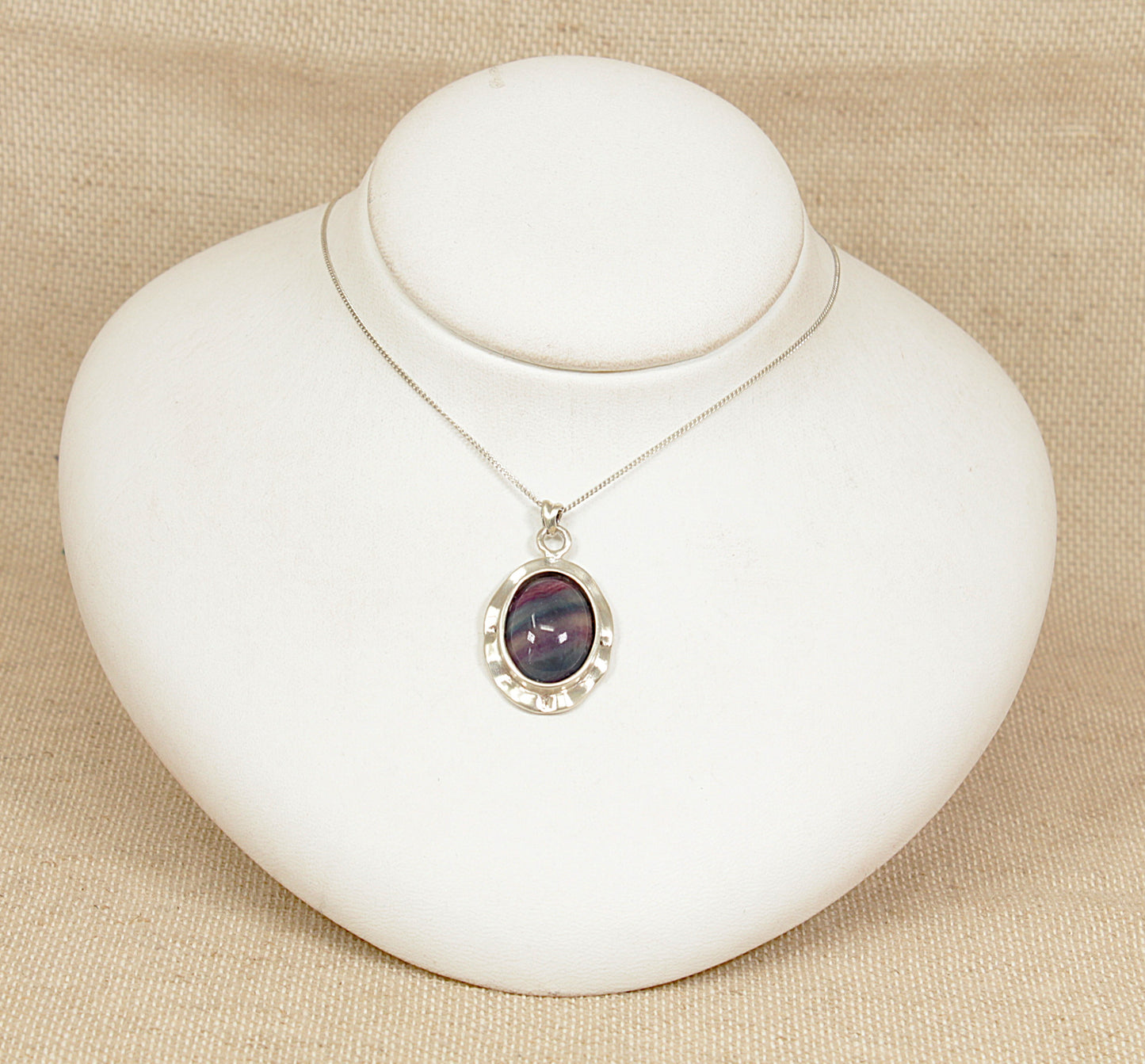 Necklace with an agate pendant on a white heart-shaped stand against a beige background