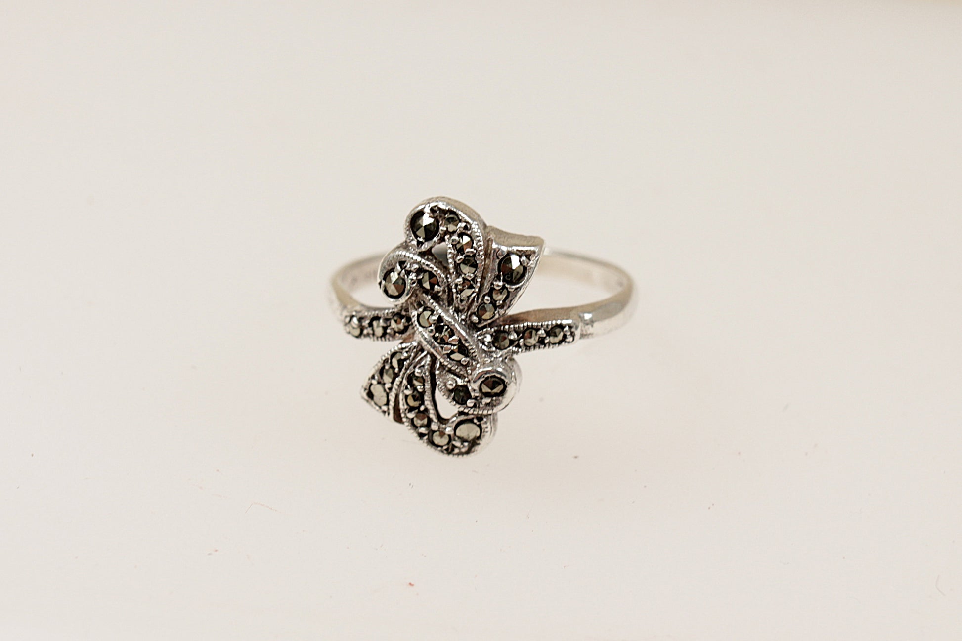 An Art Deco style silver ring with a bow design and marcasite stone embellishments, It is in excellent condition and inside the band it is stamped Silver. Circa 1930’s, UK Finger size: P.