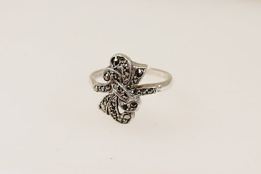 An Art Deco style silver ring with a bow design and marcasite stone embellishments, It is in excellent condition and inside the band it is stamped Silver. Circa 1930’s, UK Finger size: P.