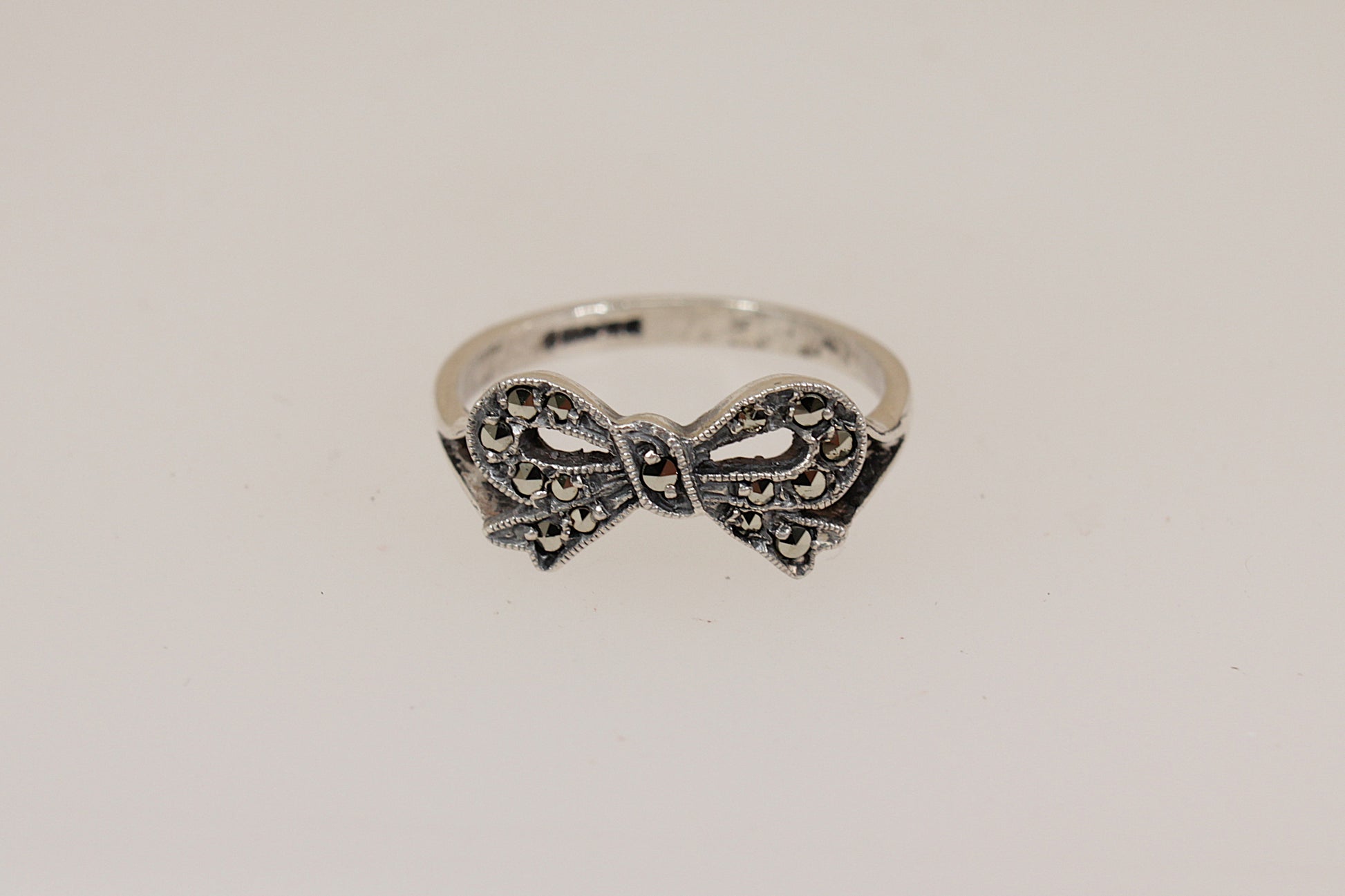 Silver bow-shaped ring on a light gray background
