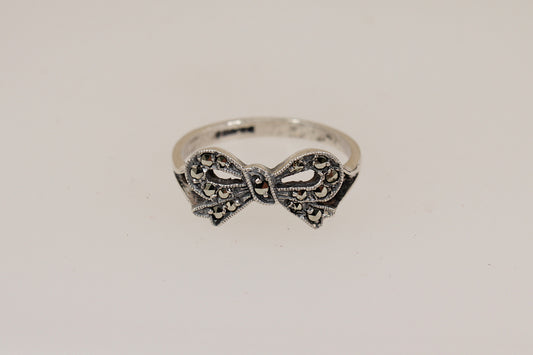 Silver bow-shaped ring on a light gray background