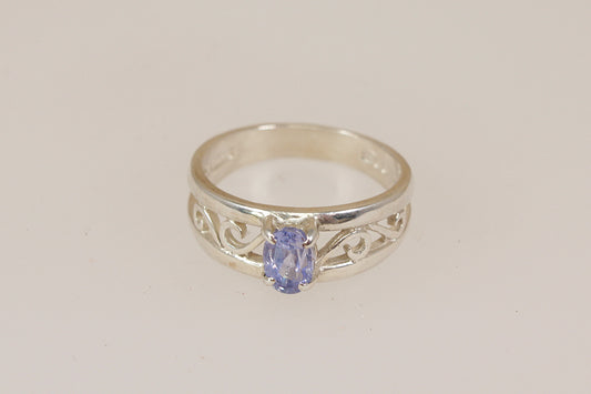 Silver ring with a cornflower blue sapphire gemstone on a light beige background