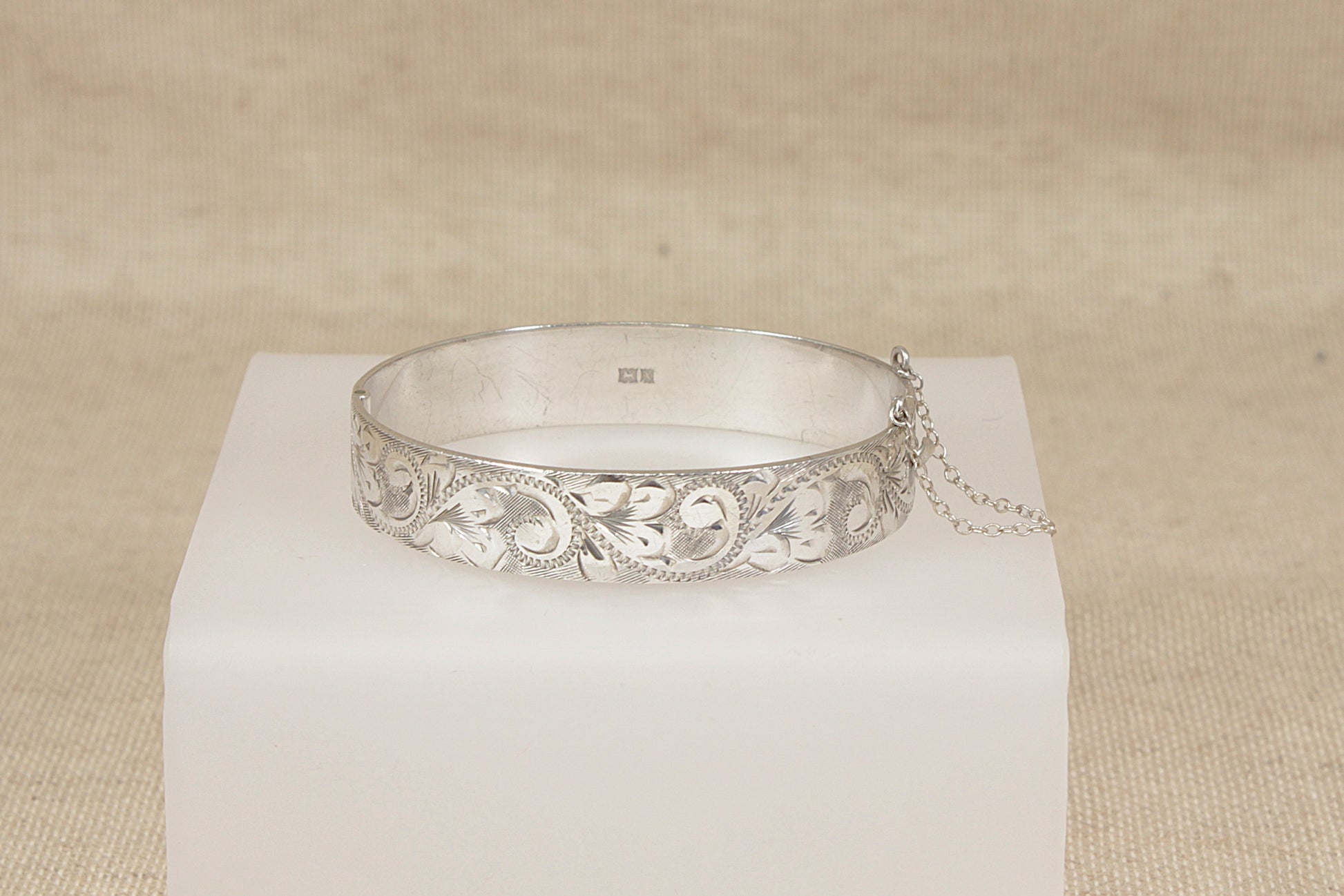 Vintage Silver bracelet cuff bangle on a white cube with a beige background