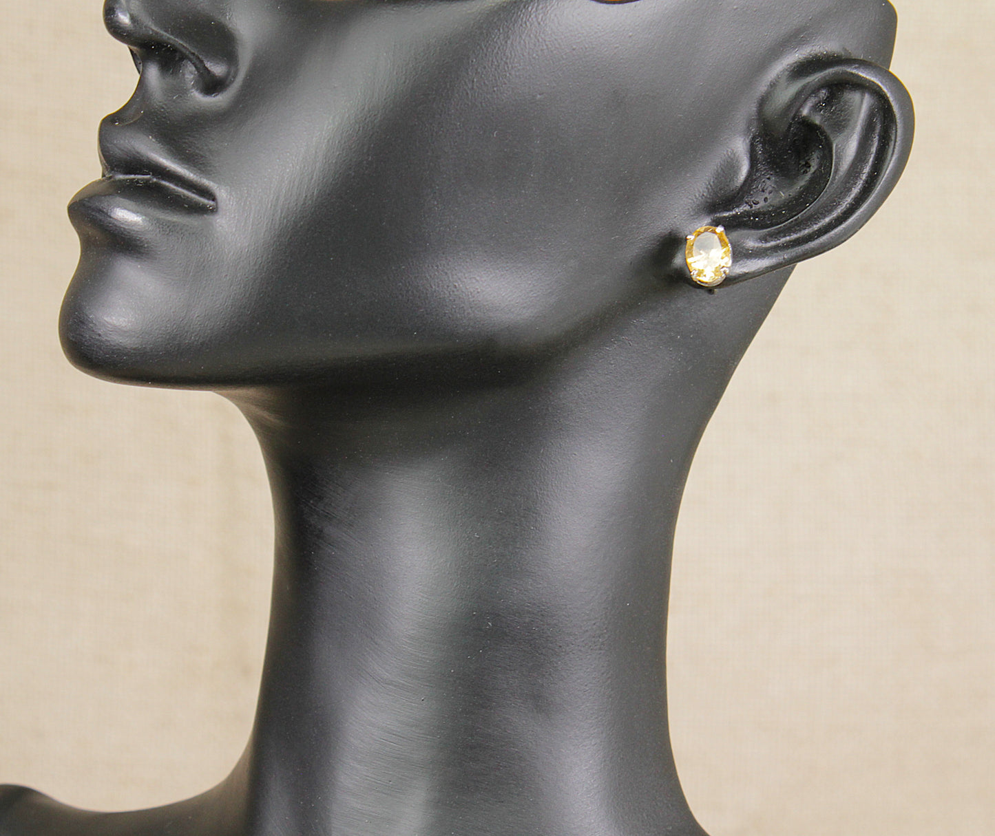 Mannequin head with a silver citrine  earring on a beige background
