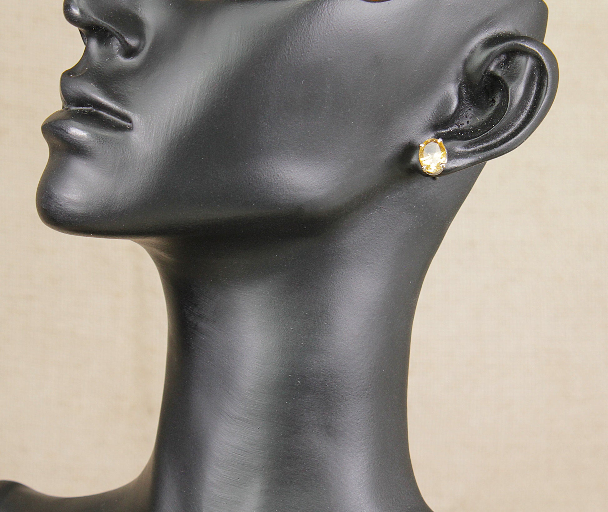 Mannequin head with a silver citrine  earring on a beige background