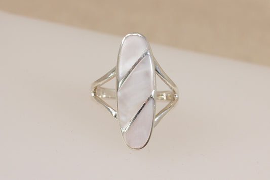 Silver ring with a geometric design of inset mother of pearl on a beige background