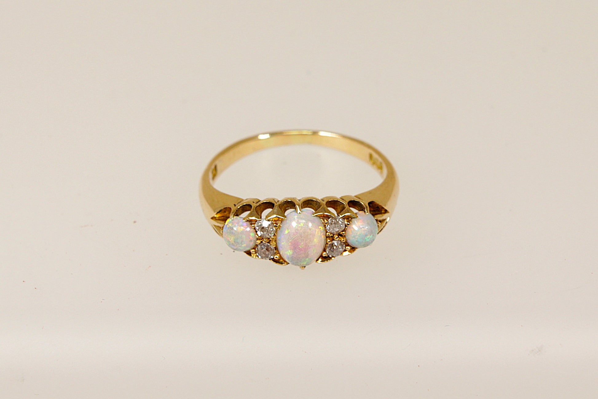 An Edwardian 18ct gold ring with three cabochon cut fire opals and four rose cut diamonds set in a galleried design, The ring is in excellent condition and inside the band it is stamped 18 for 18ct Gold. It also has the maker mark A & W. 
UK Finger size P.