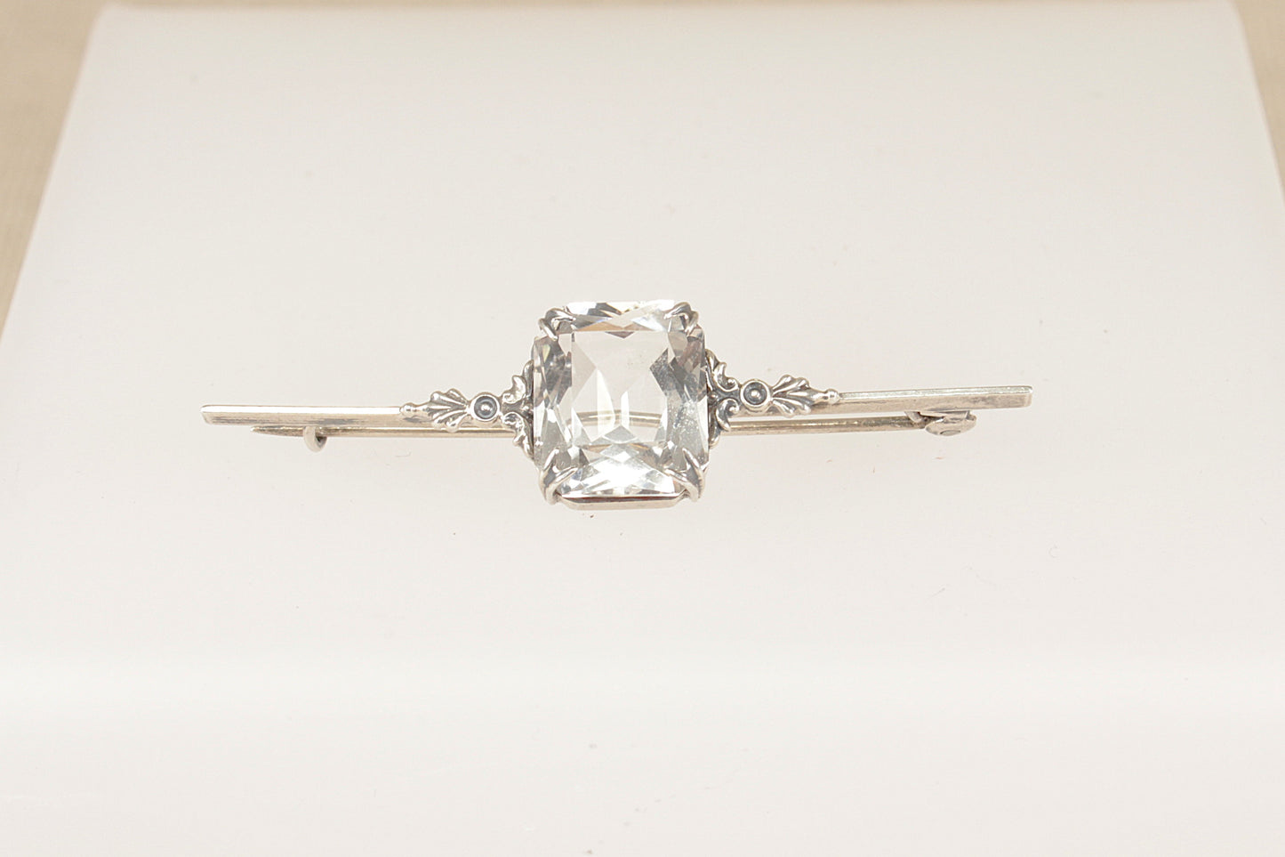 An elegant Edwardian Silver bar brooch features a striking emerald-cut Rock Crystal on a white background