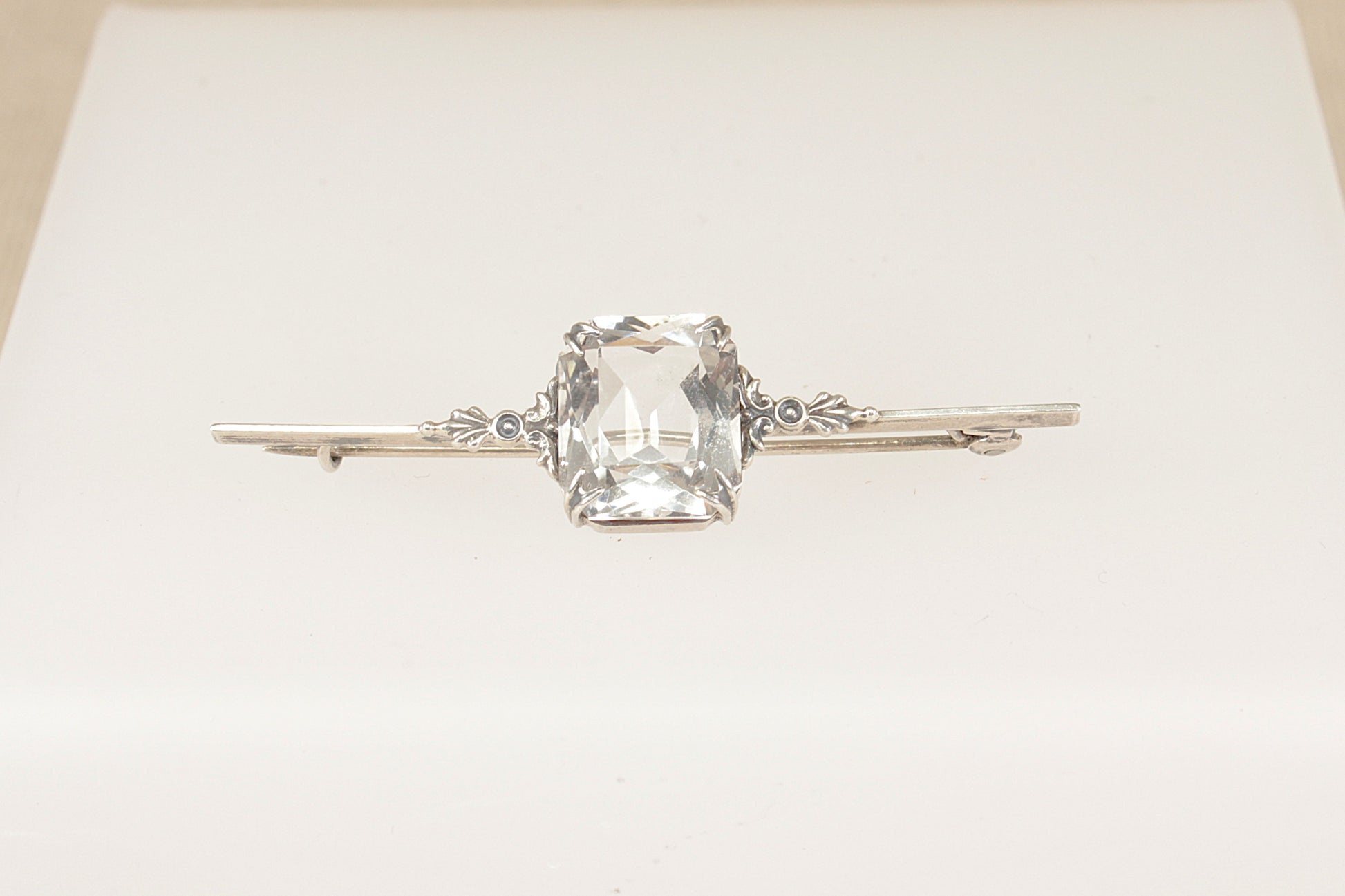 An elegant Edwardian Silver bar brooch features a striking emerald-cut Rock Crystal on a white background