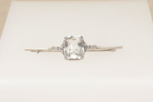 An elegant Edwardian Silver bar brooch features a striking emerald-cut Rock Crystal on a white background