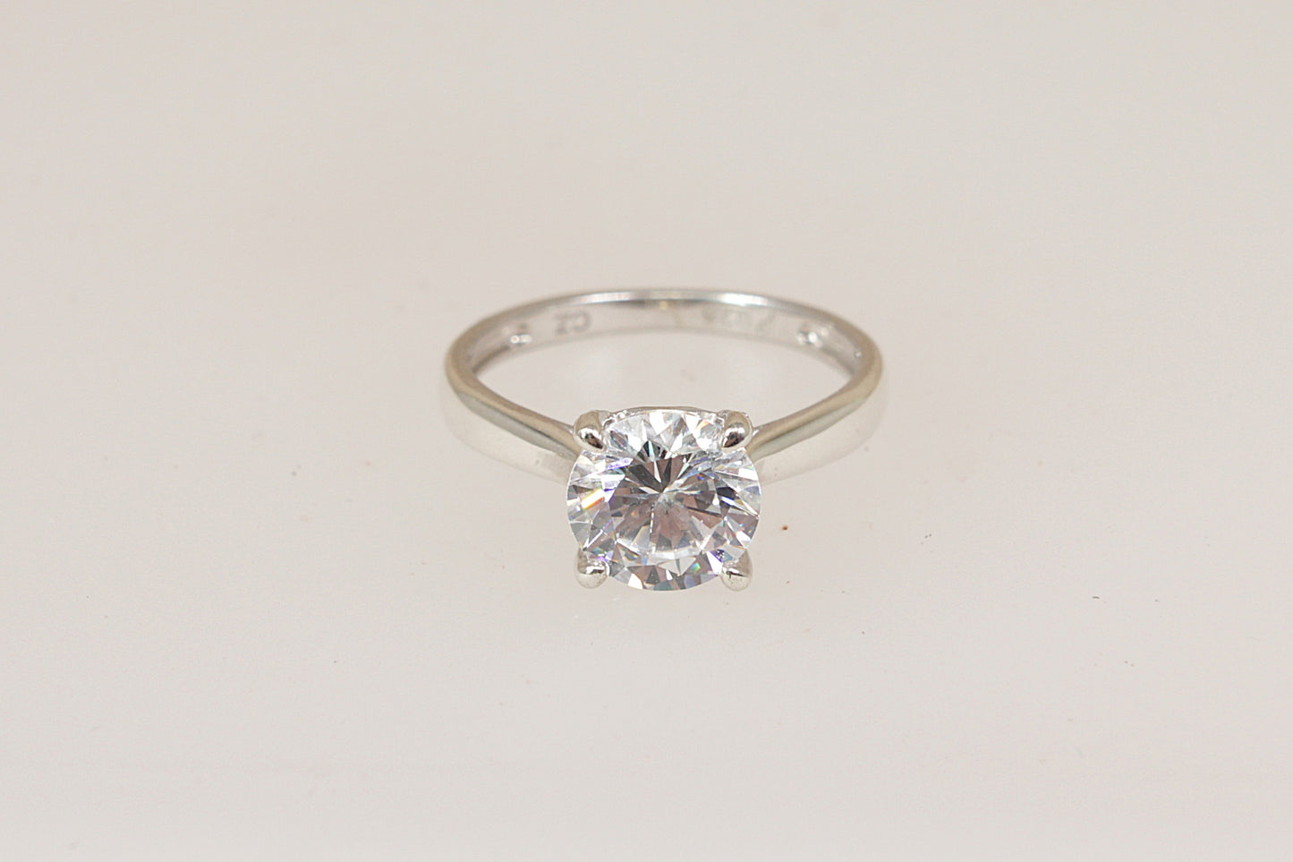 Silver solitaire ring with a cubic zirconia diamond simulant gemstone on a light gray background