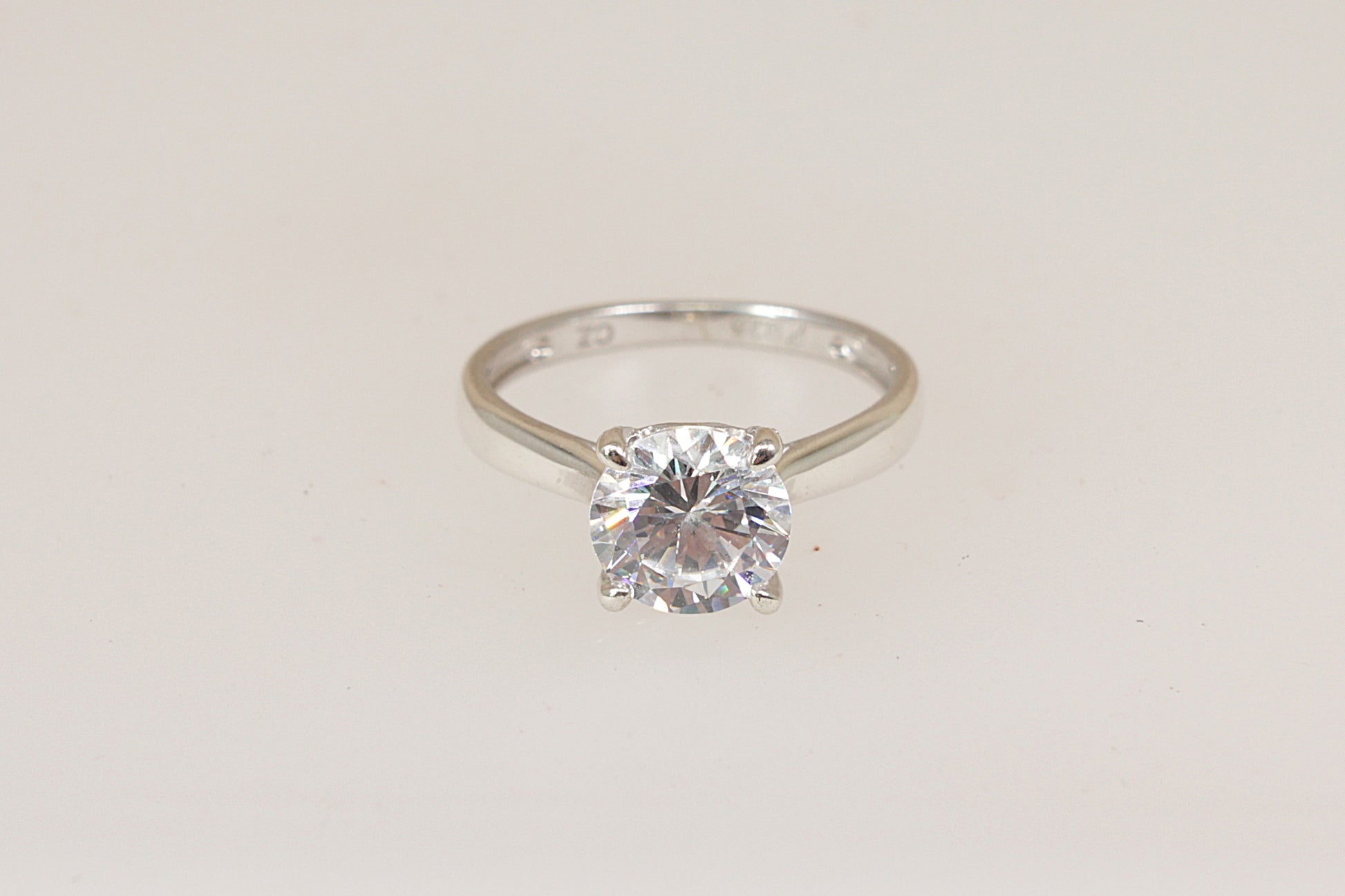 Silver solitaire ring with a cubic zirconia diamond simulant gemstone on a light gray background