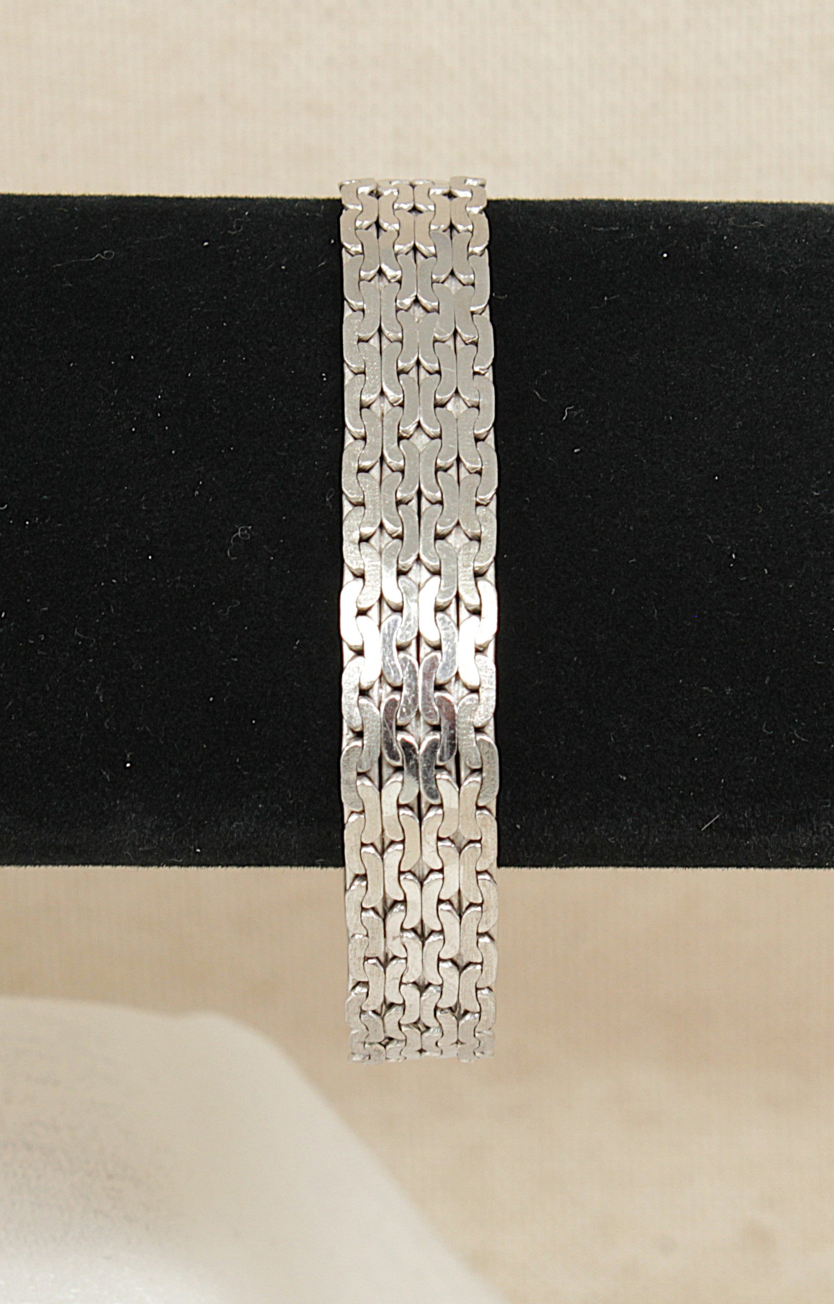 Silver designer bracelet on a black and beige background