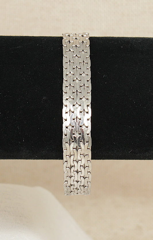 Silver designer bracelet on a black and beige background