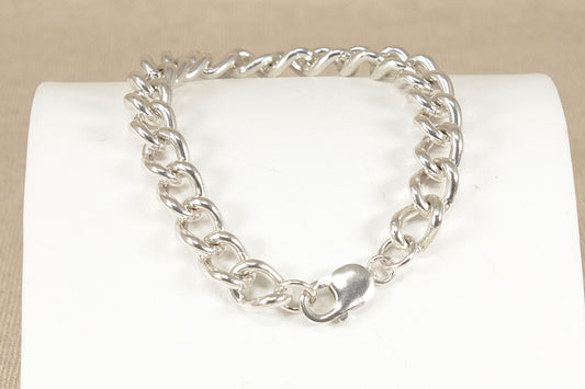 Silver chain bracelet on a white cushion with a beige background