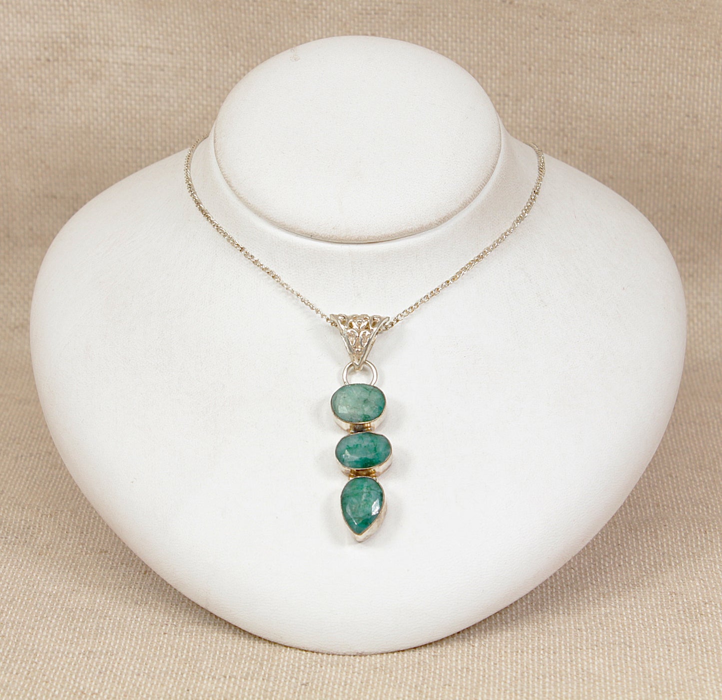 Necklace with green chrysoprase  pendant on a white stand against a beige background