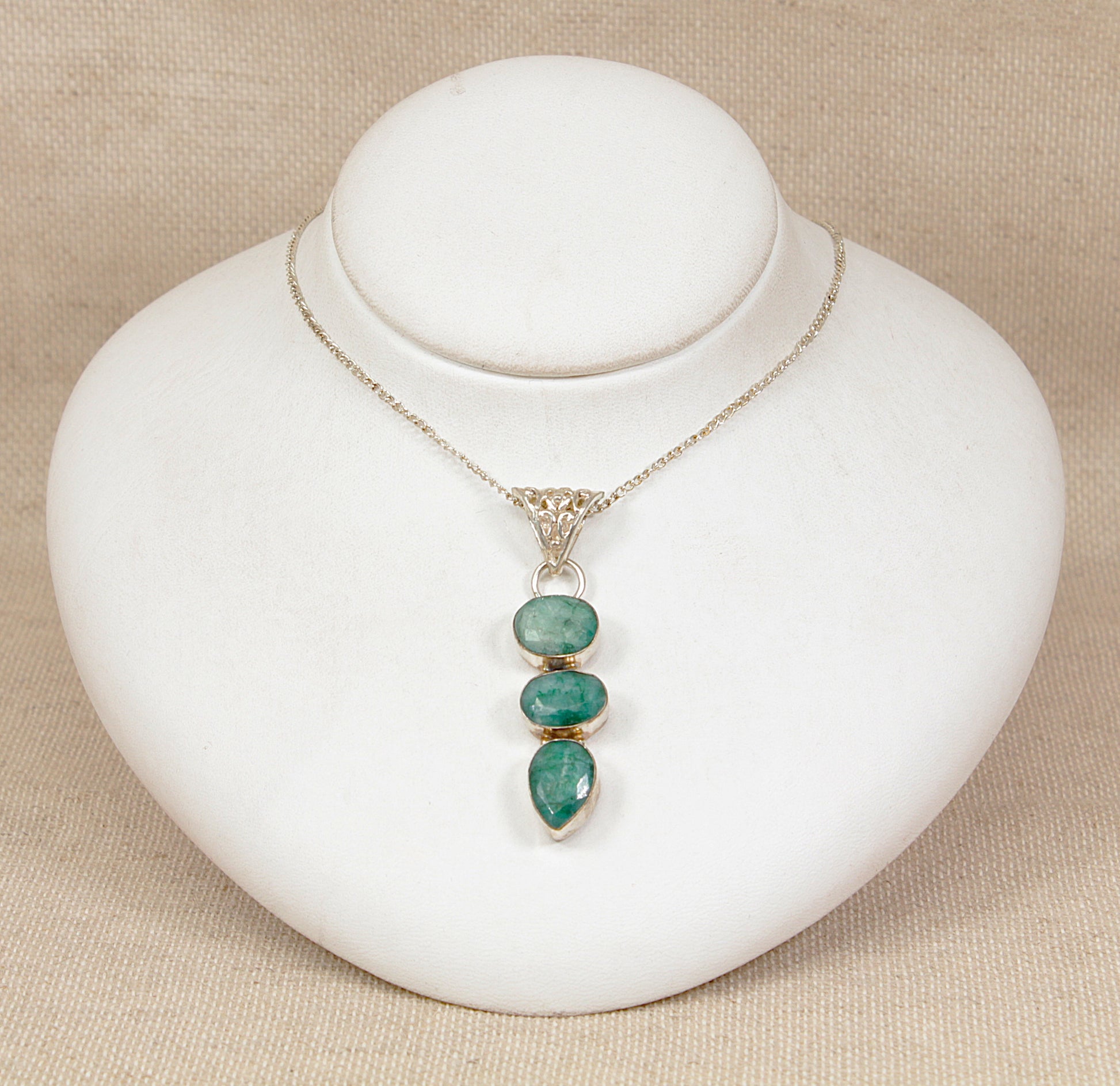 Necklace with green chrysoprase  pendant on a white stand against a beige background