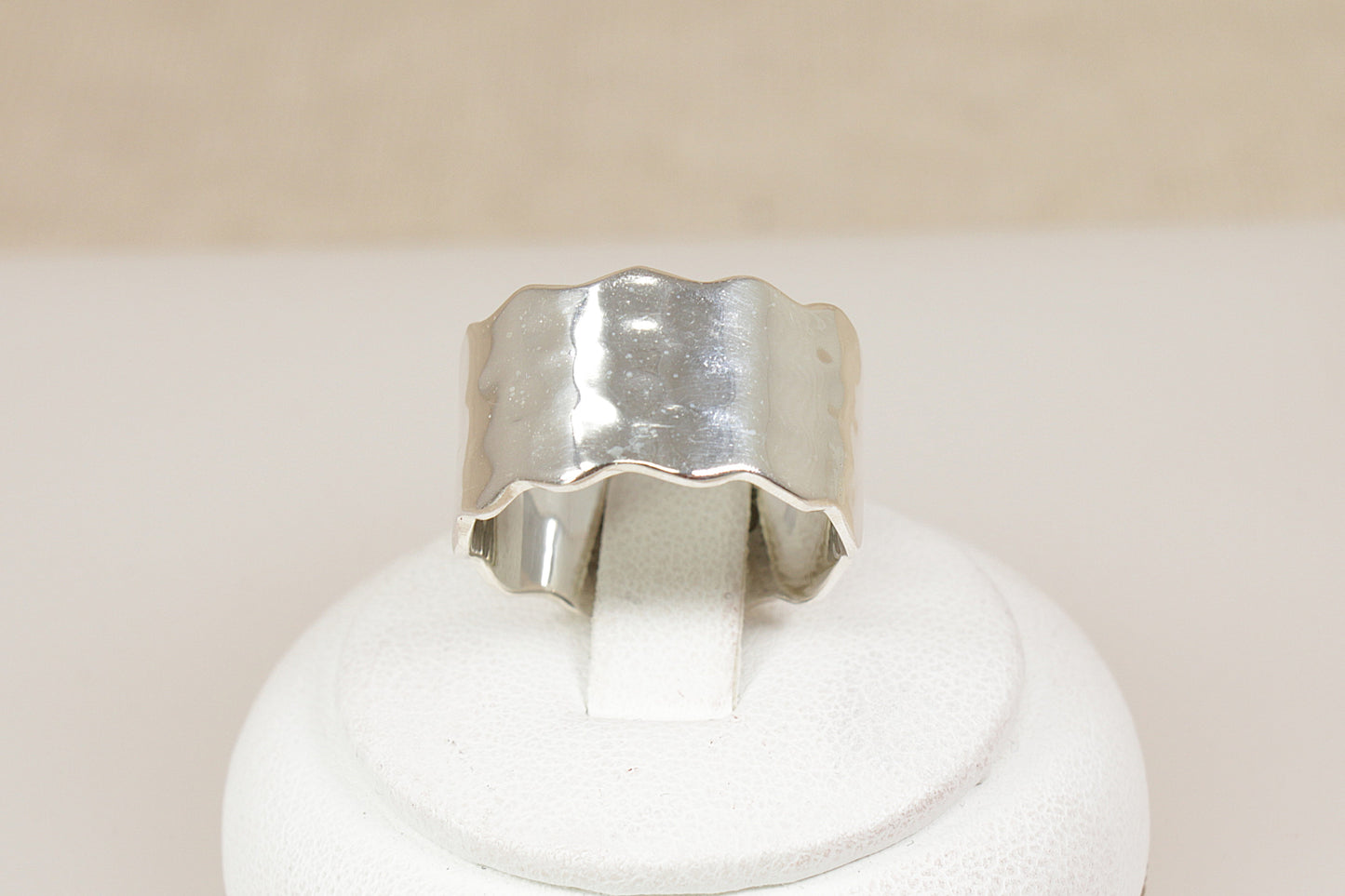 Brand new Silver band statement ring on a white stand with a beige background