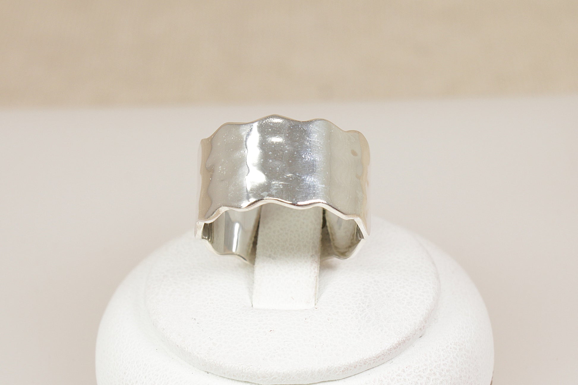 Brand new Silver band statement ring on a white stand with a beige background