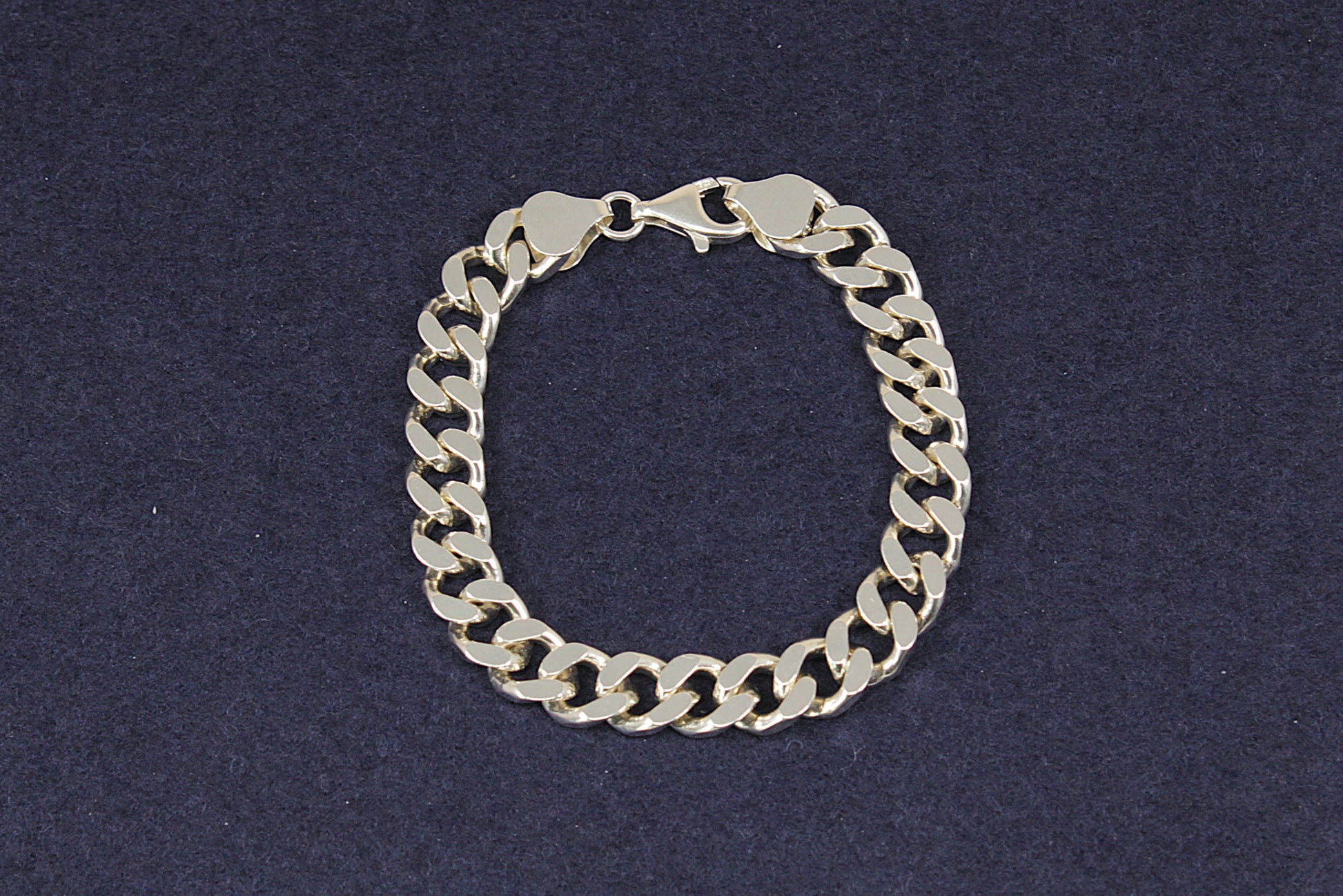 Heavy Silver curb link chain bracelet on a dark blue background