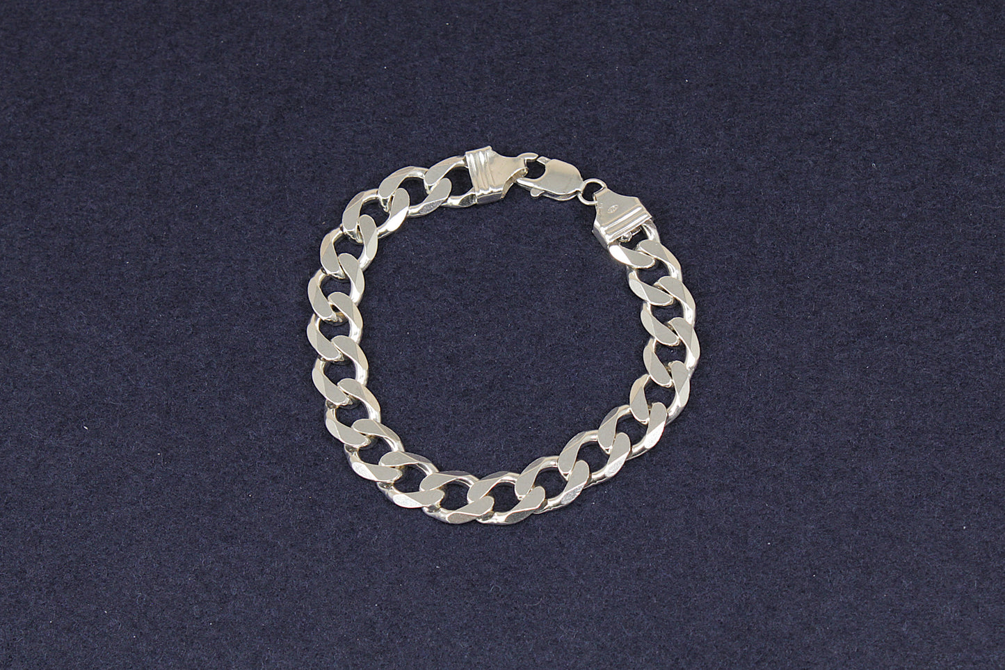 Ladies Gents Silver curb links chain bracelet on a dark blue background