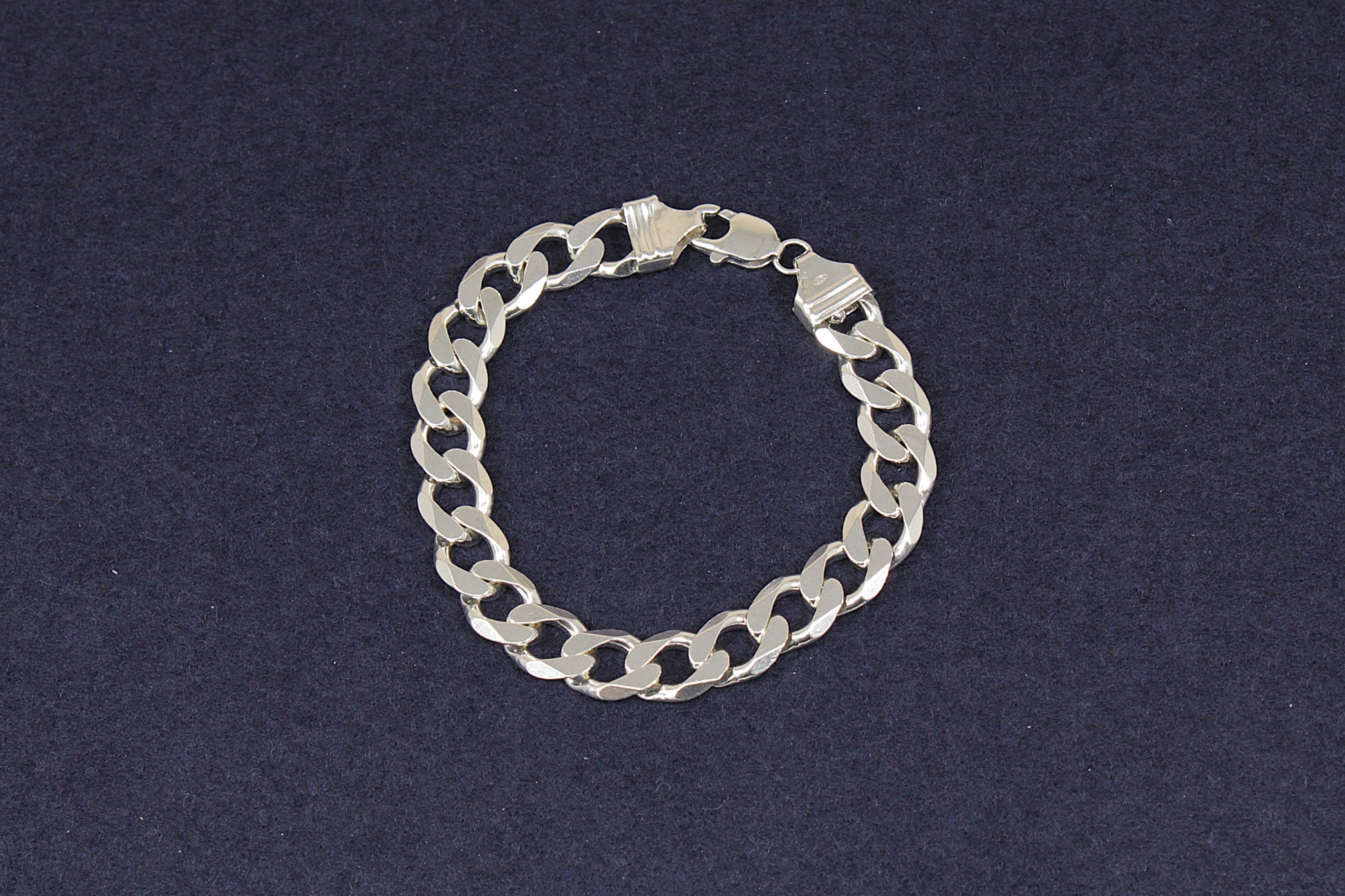 Ladies Gents Silver curb links chain bracelet on a dark blue background