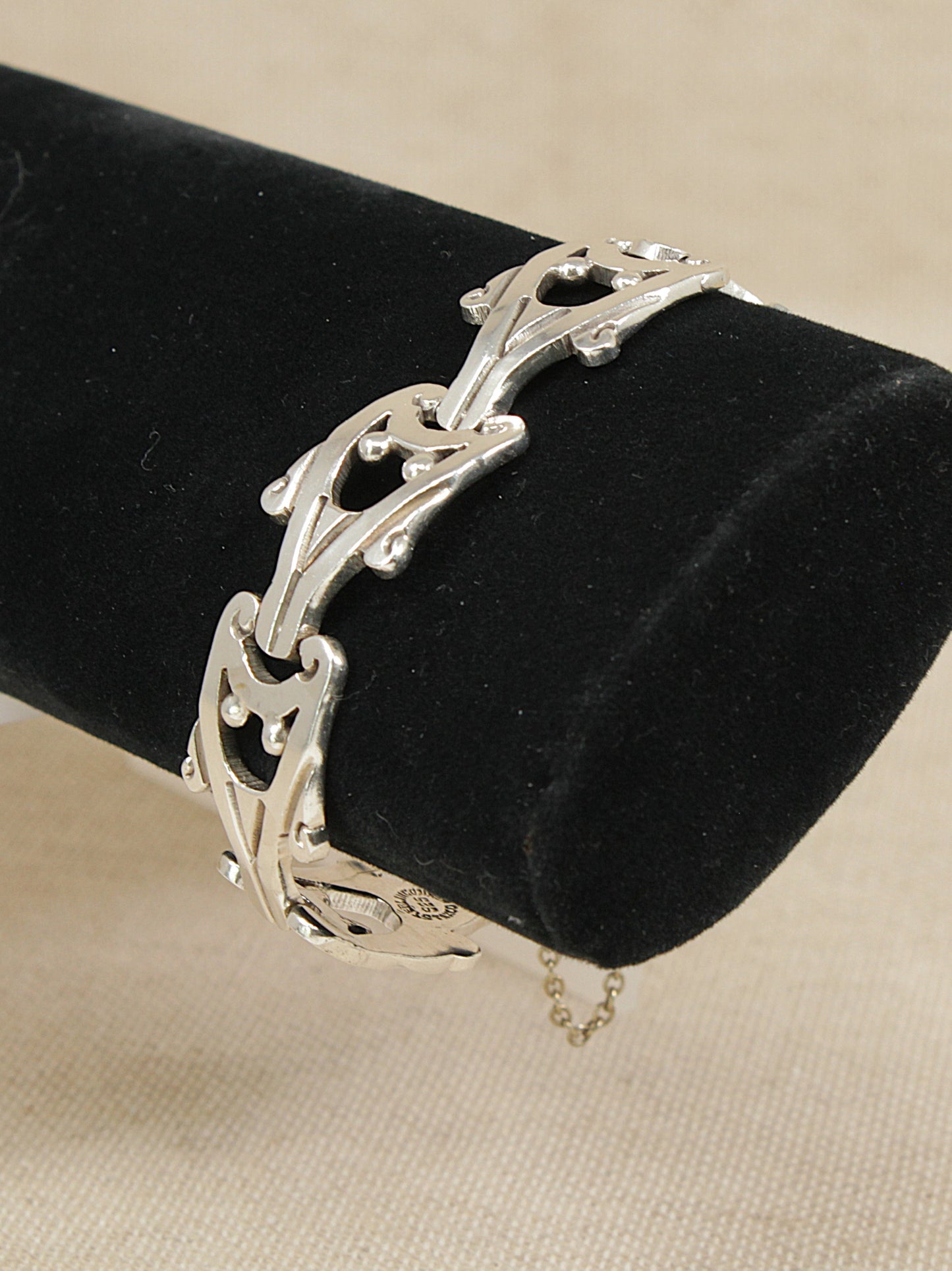 Heavy Mexican Taxco Silver bracelet on a black velvet stand with a beige background