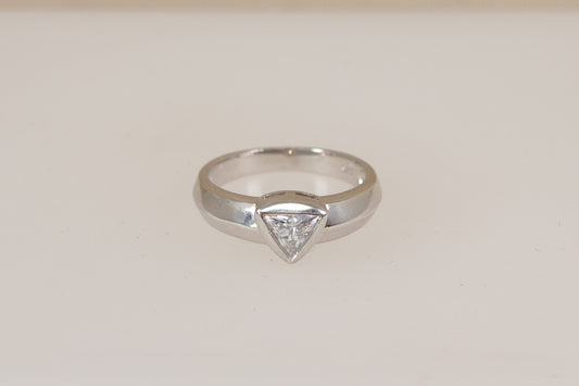 Silver ring with a triangular diamond simulant cz cubic zirconia gemstone on a light beige background