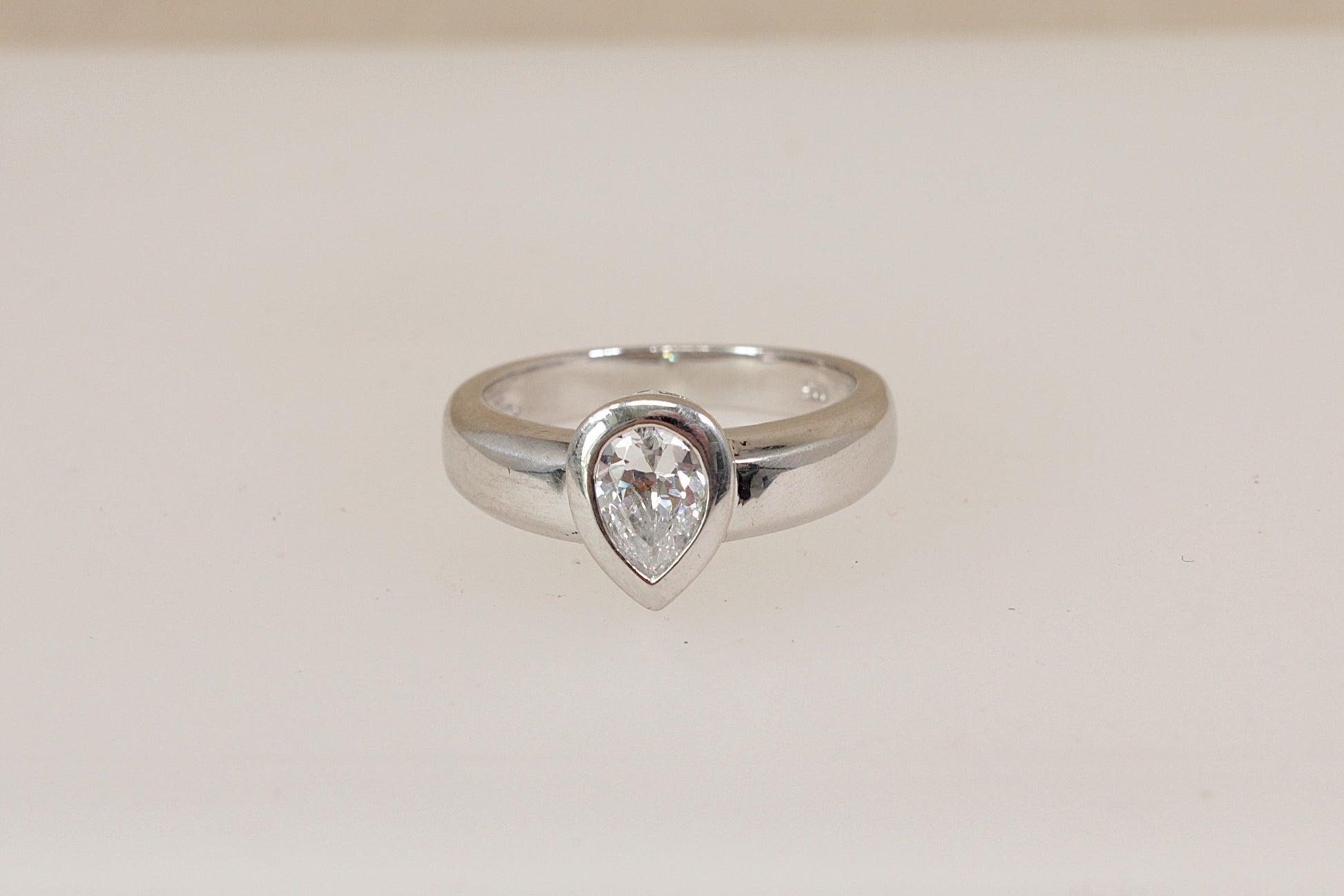 Silver ring with a teardrop-shaped cz cubic zirconia (diamond simulant) gemstone on a light beige background