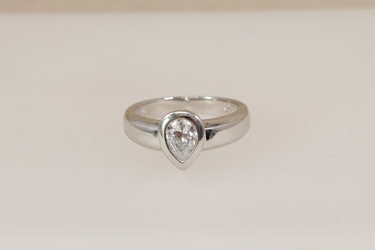 Silver ring with a teardrop-shaped cz cubic zirconia (diamond simulant) gemstone on a light beige background