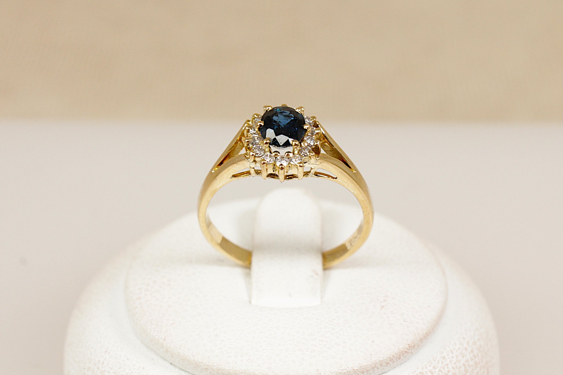 An 18ct yellow gold sapphire and diamond 'Diana' style ring, the ring has an estimated 0.50 carat central blue sapphire that is surrounded with fourteen brilliant round cut diamonds, UK finger size M.