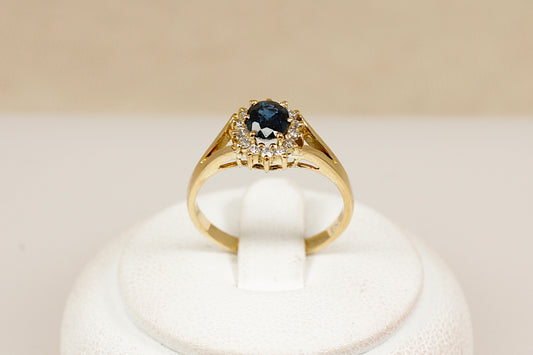 An 18ct yellow gold sapphire and diamond 'Diana' style ring, the ring has an estimated 0.50 carat central blue sapphire that is surrounded with fourteen brilliant round cut diamonds, UK finger size M.