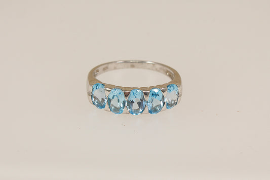 Silver ring with blue topaz gemstones on a beige background
