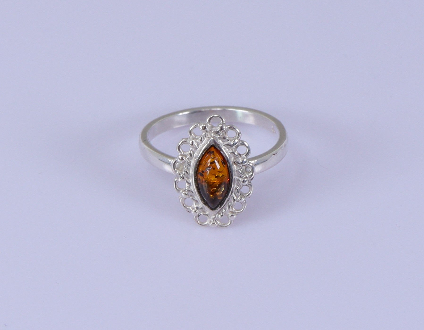 A marquise-shaped amber ring set in a silver mounting, with the ring's band displaying a 925 sterling silver stamp.