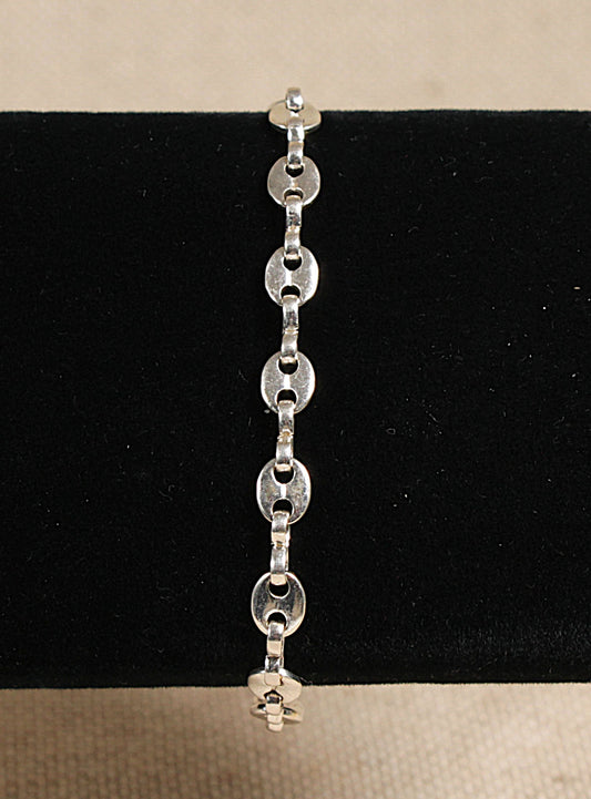 A silver anchor chain link bracelet with a lobster clasp fastening, displayed against a black background.