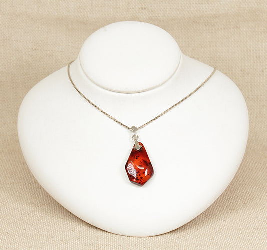 A truly stunning piece of wearable art, this French-designed Baltic amber pendant is set in 835 continental silver and suspended from a classic 22-inch 925 sterling silver box chain. The pear-shaped amber is polished to a smooth finish, showcasing its rich golden hue and captivating natural inclusions of ancient vegetation, making each piece one-of-a-kind.