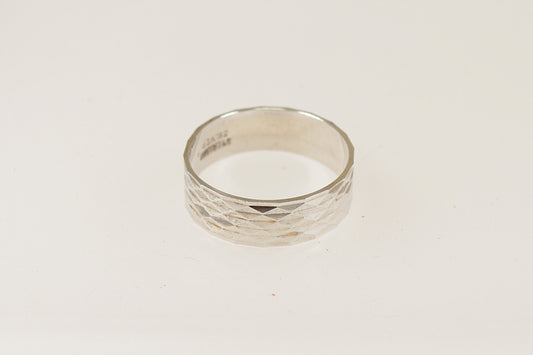 A silver band ring with an engine turned pattern, displayed against a white background.