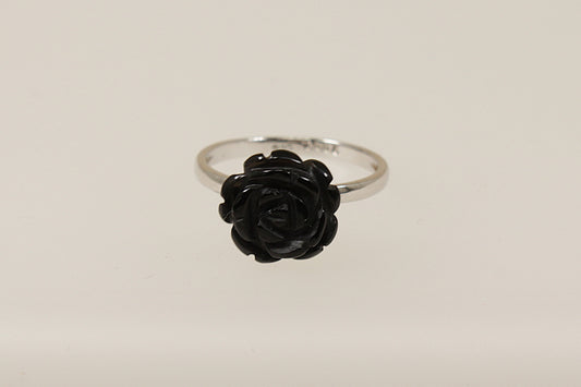 A silver ring with a black carved flower in the form of a rose, displayed against a white background.
