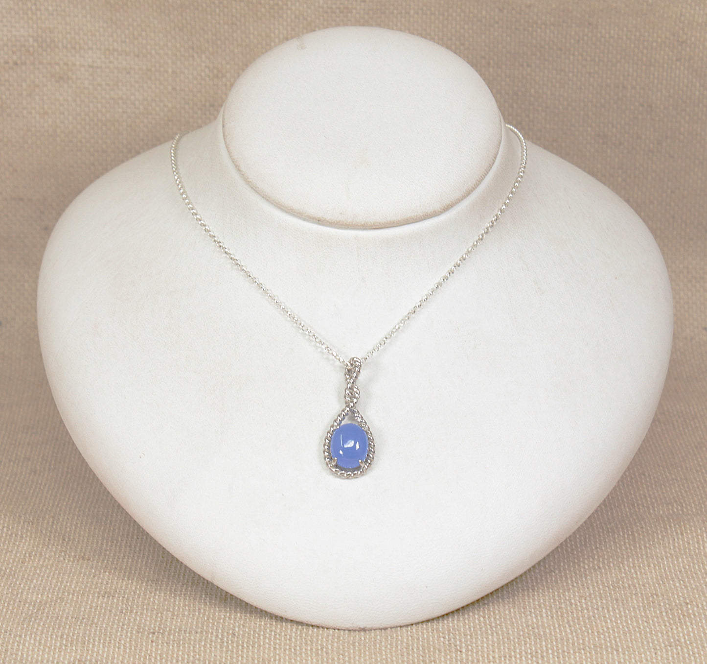 Silver necklace with a blue pendant on a white jewelry display