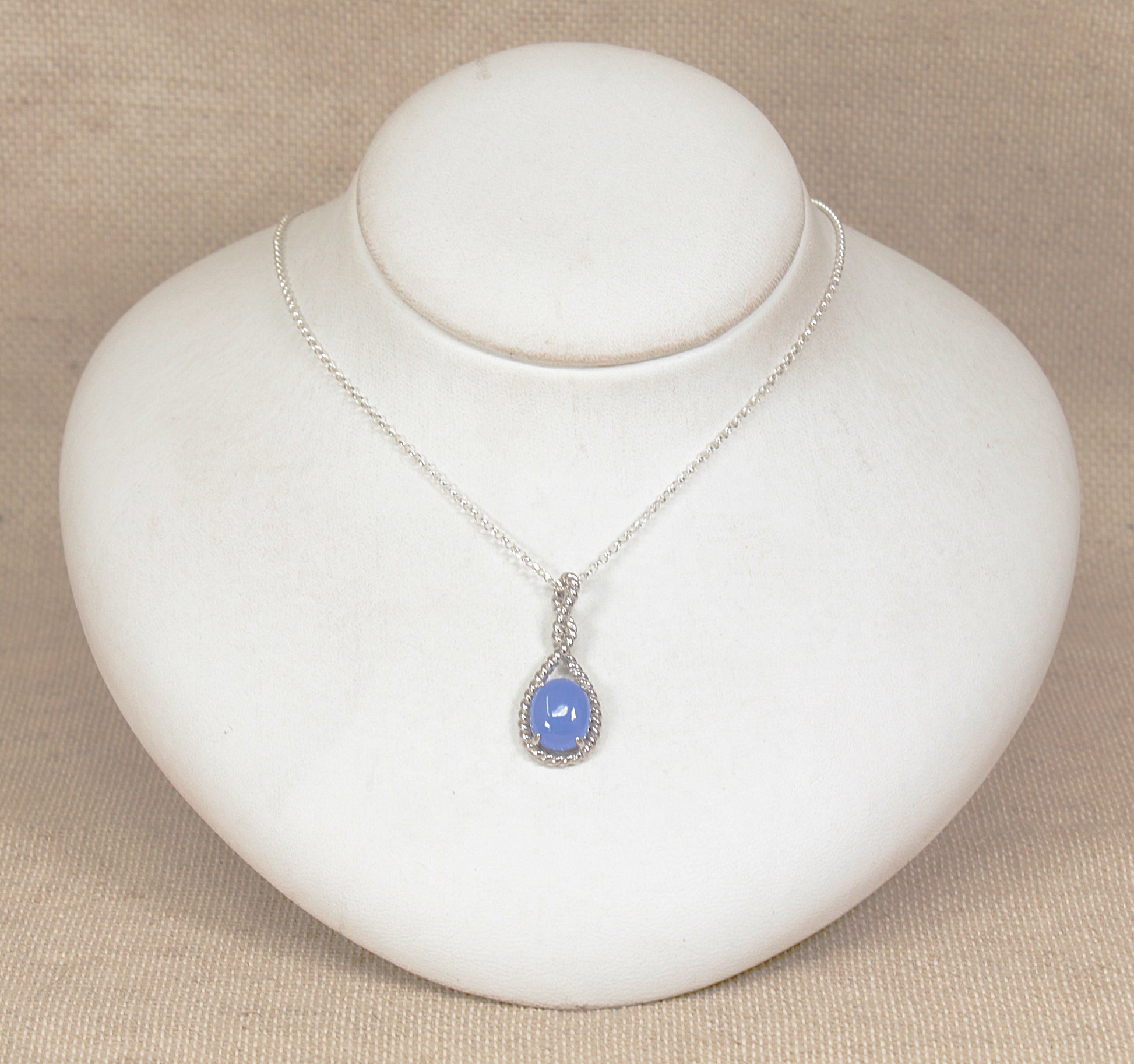 Silver necklace with a blue pendant on a white jewelry display