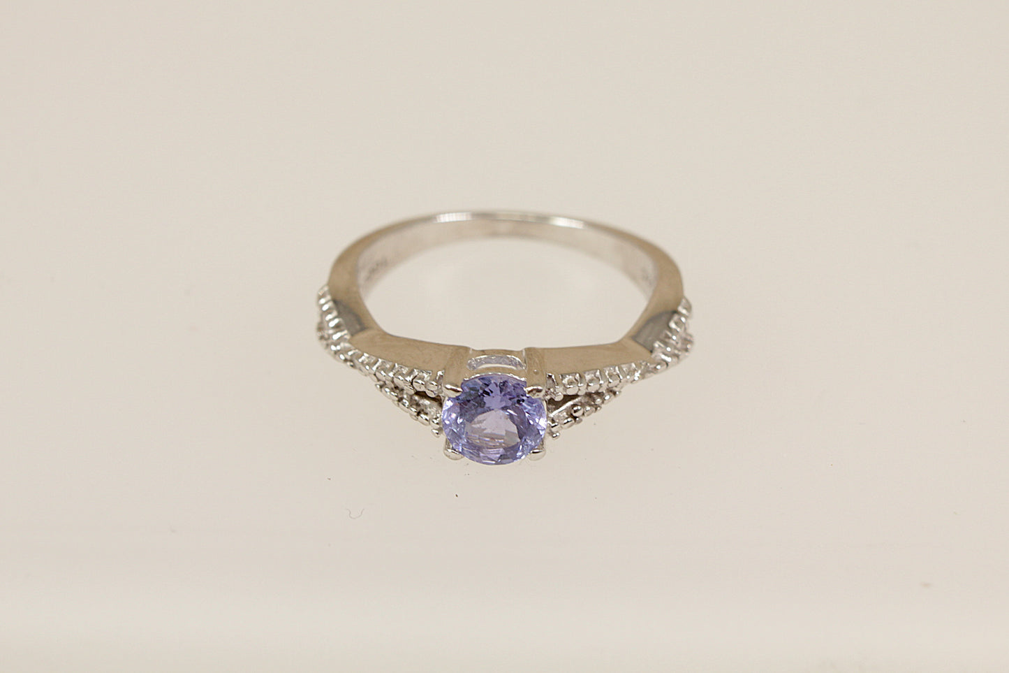 Silver ring with a purple gemstone on a light beige background