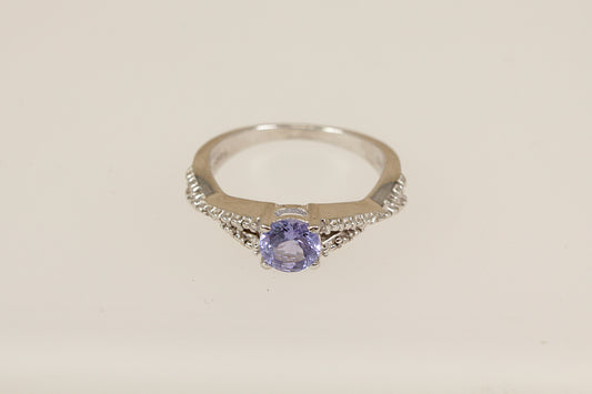 Silver ring with a purple gemstone on a light beige background