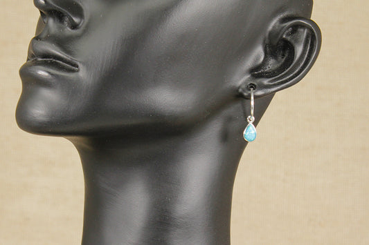 Mannequin head with a hoop earring featuring a blue opal gemstone on a beige background