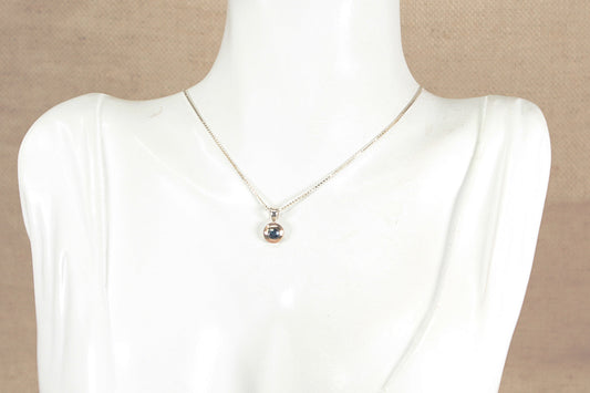 Necklace with a gold plated silver blue sapphire gemstone pendant on a mannequin against a beige background