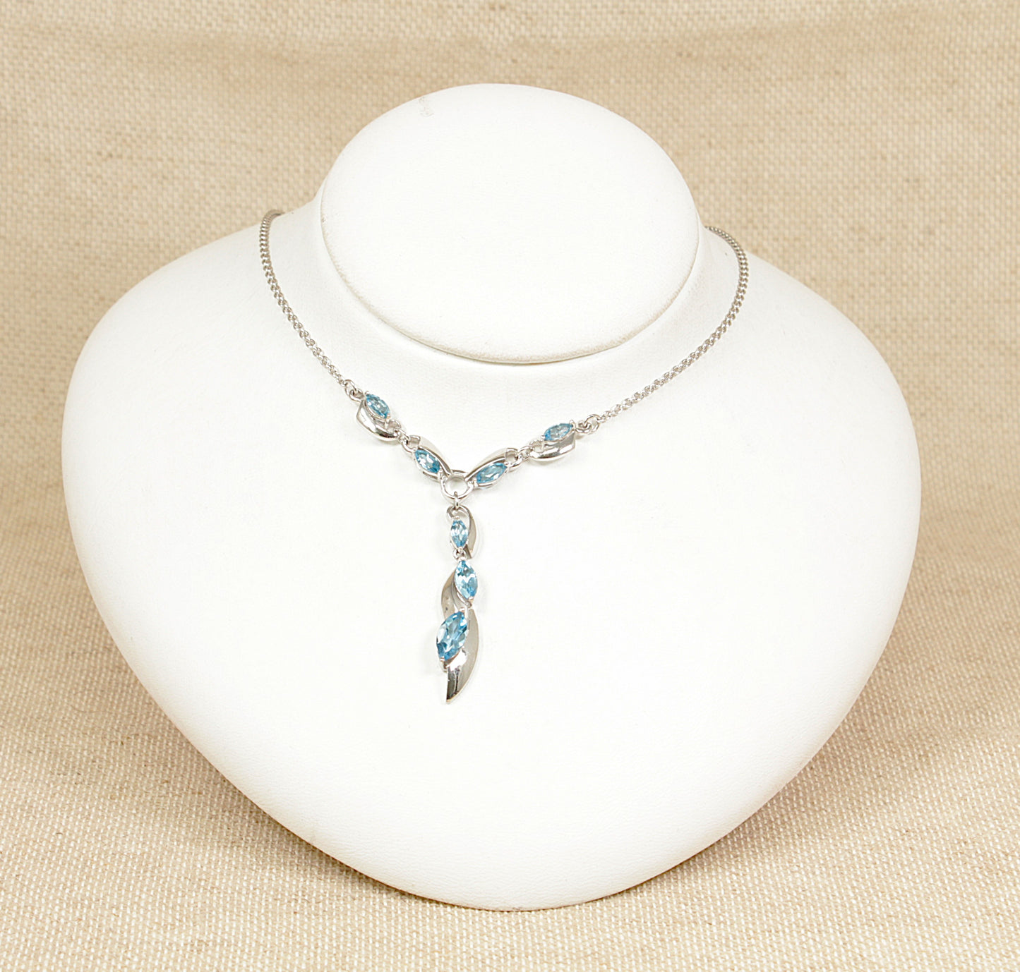 A sterling silver necklet necklace with blue spinel gemstones displayed on a white mannequin bust.