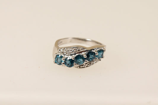 A sterling silver ring with five round blue topaz gemstones set across the band in a graceful curve with claw settings.