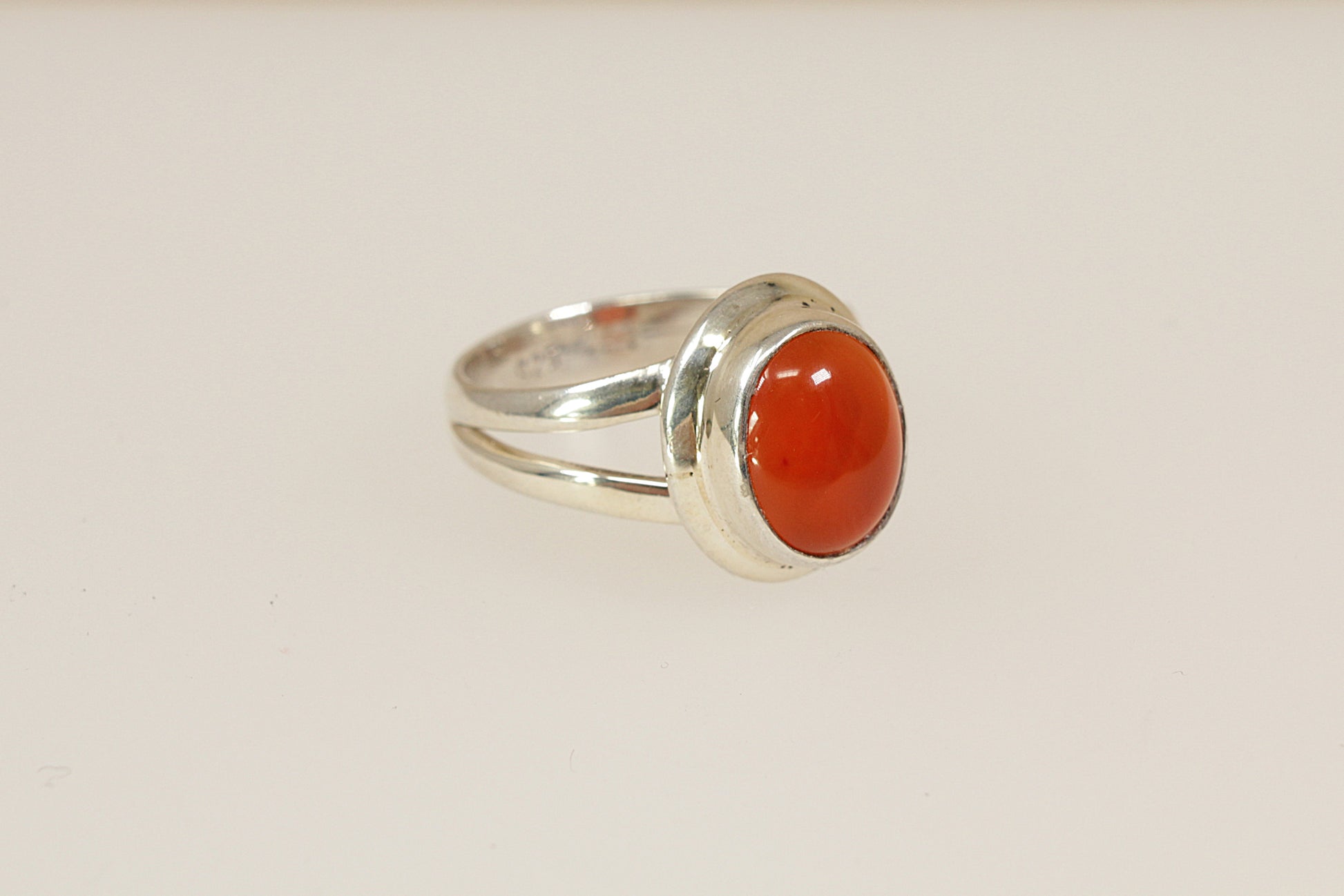 Silver ring with a centre carnelian gemstone on a light beige background