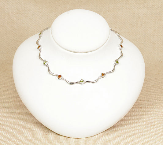 A sterling silver necklace with alternating square bezel-set citrine and peridot gemstones, displayed on a white mannequin.
