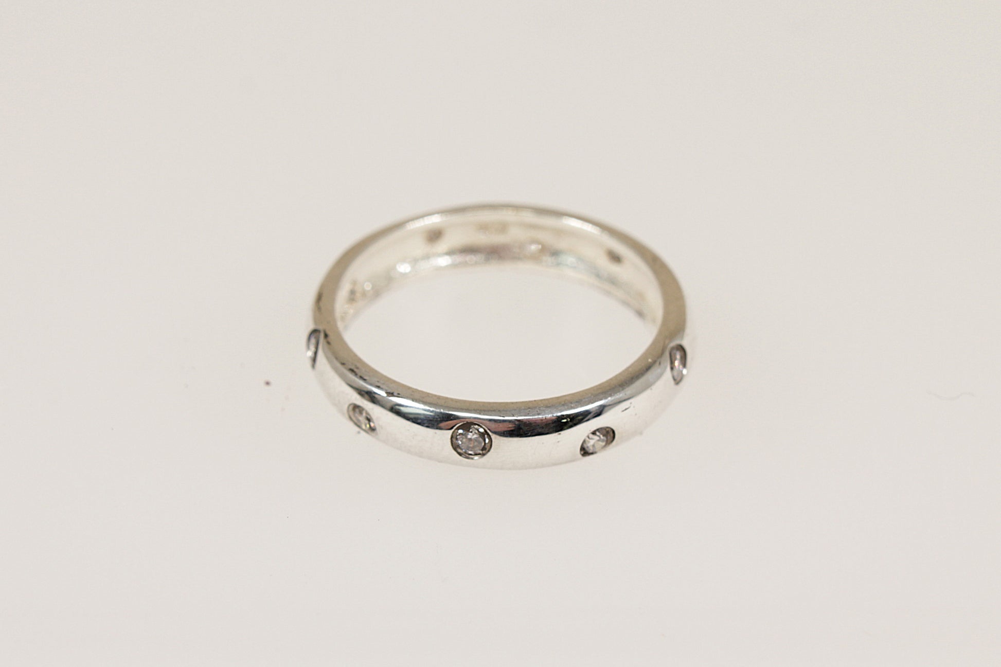 This stylish and elegant band ring has inset crystals running all around the band, combined with the rounded edges, this creates a modern yet timeless look. The polished smooth finish provides a comfortable feel for everyday wear and it would make a perfect stacking ring. It is stamped 925 for sterling silver.